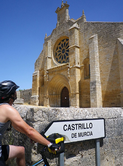 Cyclist looking at a Romanesque church on the Camino de Santiago