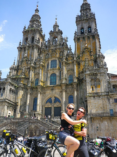 Young couple bicycle travelers rejoice outside the cathedral at Santiago de Compostella